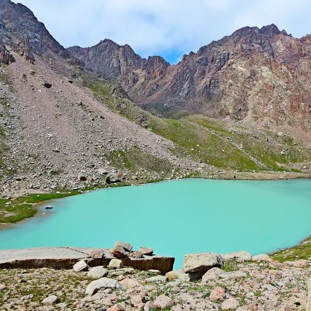 Отдалённое ледниковое озеро в долине Аксай на 3350м, тёмная вода отражает скальные стены