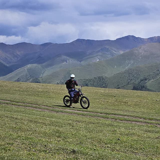 Группа райдеров пересекает открытое плато, на горизонте горы