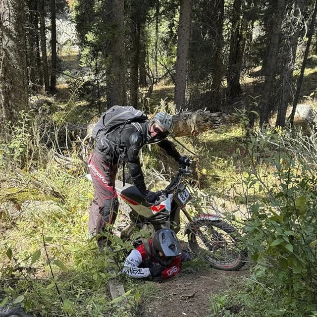 Райдеры толкают нагруженные байки через снежное поле в конце лета