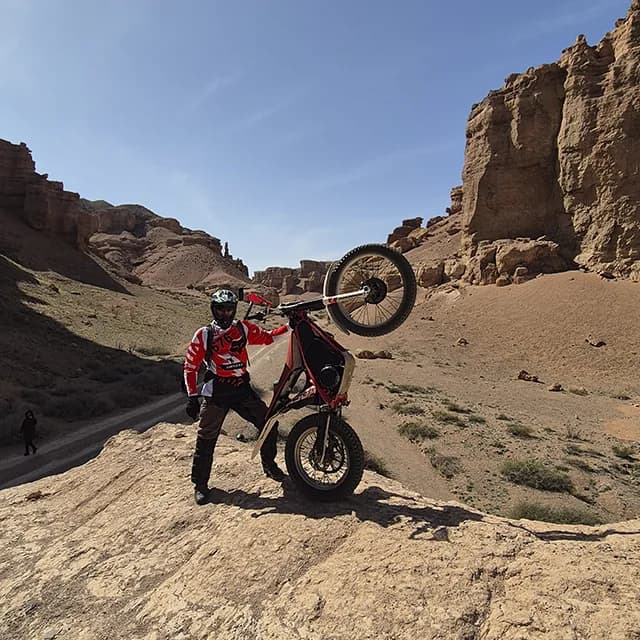 Электробайк едет по песчаному дну каньона к реке Чарын