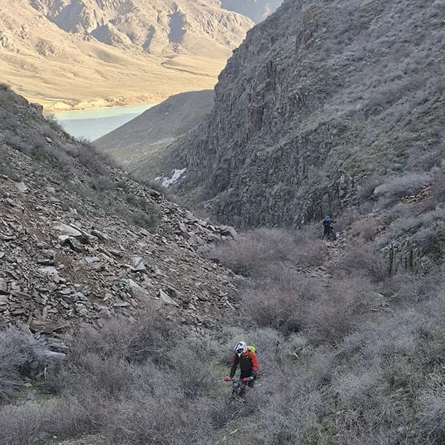 Райдер аккуратно пробирается по сыпучей осыпи прямо над глубокой водой