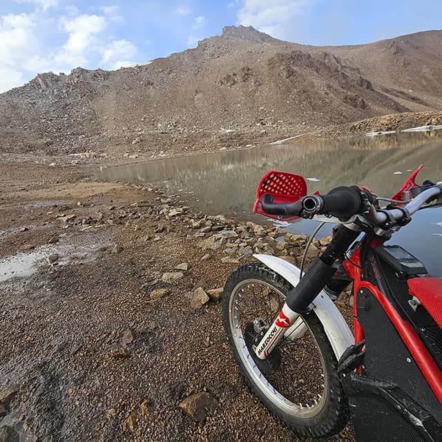 Снежные пятна на тёмных скалах у озера даже в разгар лета