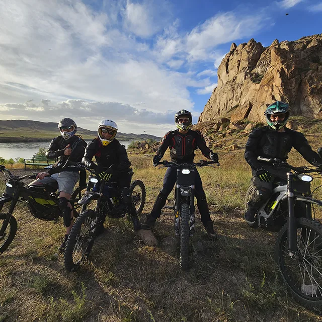 Riders navigating technical rock sections along the Ili River cliffs